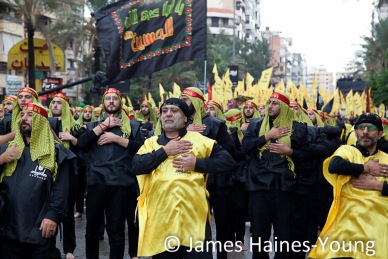 Hezbollah supporters raise their hands and beat their chests in time to chants as they take part in an Ashura procession
